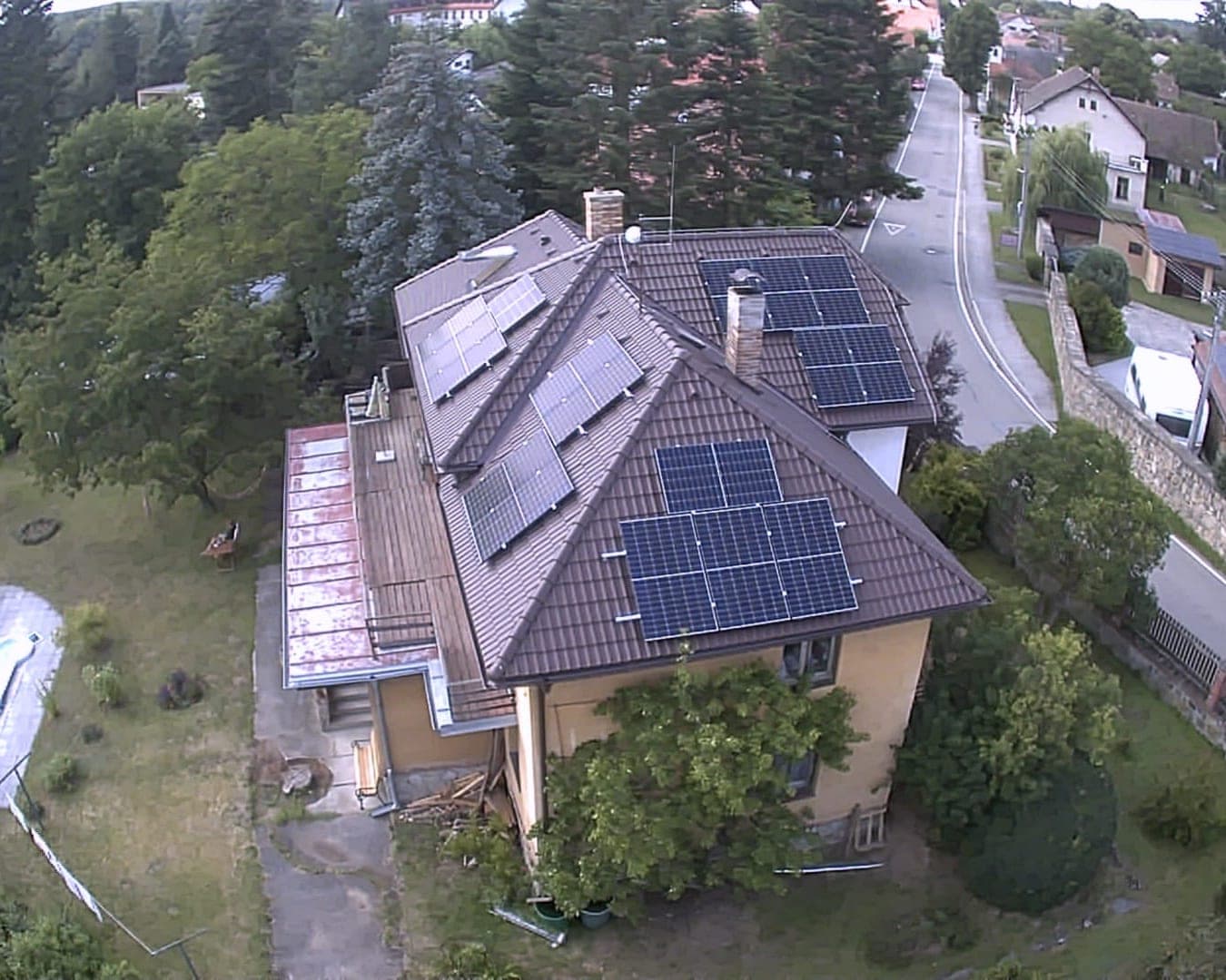 Pohled z výšky na rodinný dům s fotovoltaickými panely na taškové střeše uprostřed obce, Zvíkovské Podhradí