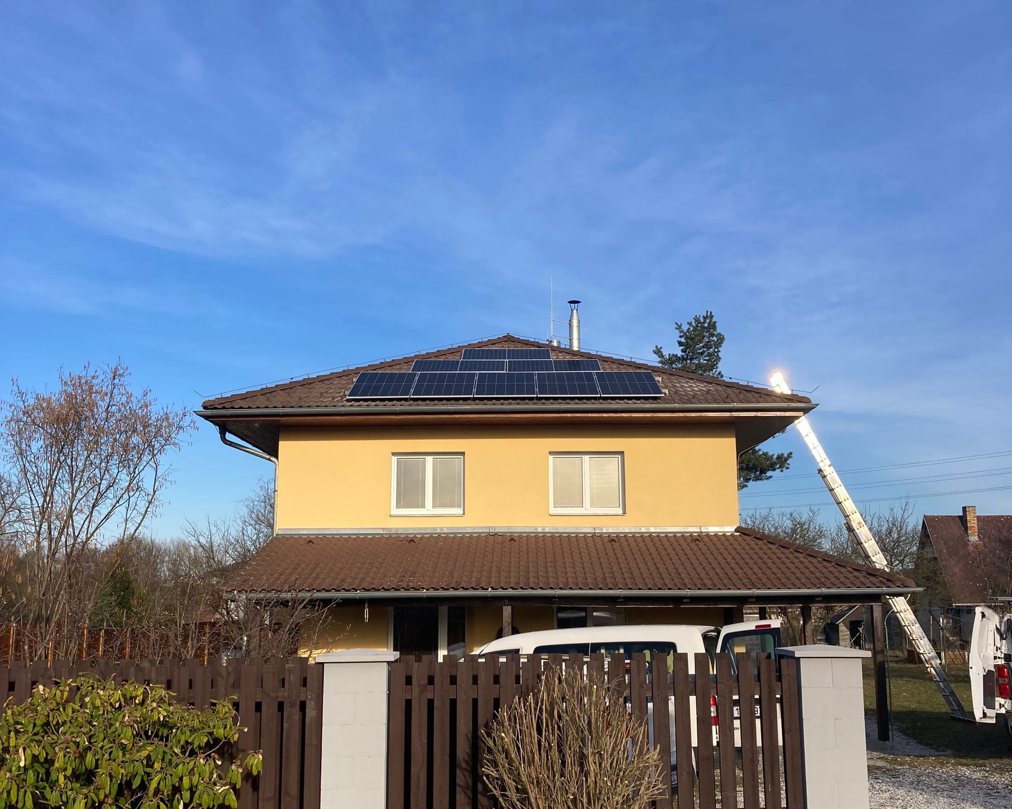 Rozšířené pole fotovoltaických panelů na střeše žlutého patrového rodinného domu, Mutěnice