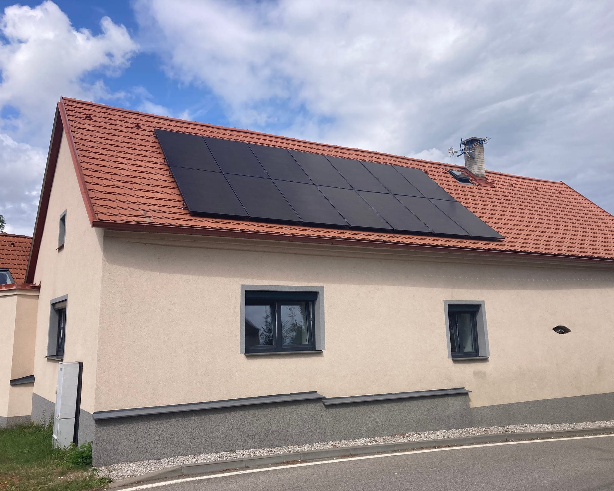 Souvislé pole fotovoltaických panelů na červené taškové střeše podélného rodinného domu, Kozlov