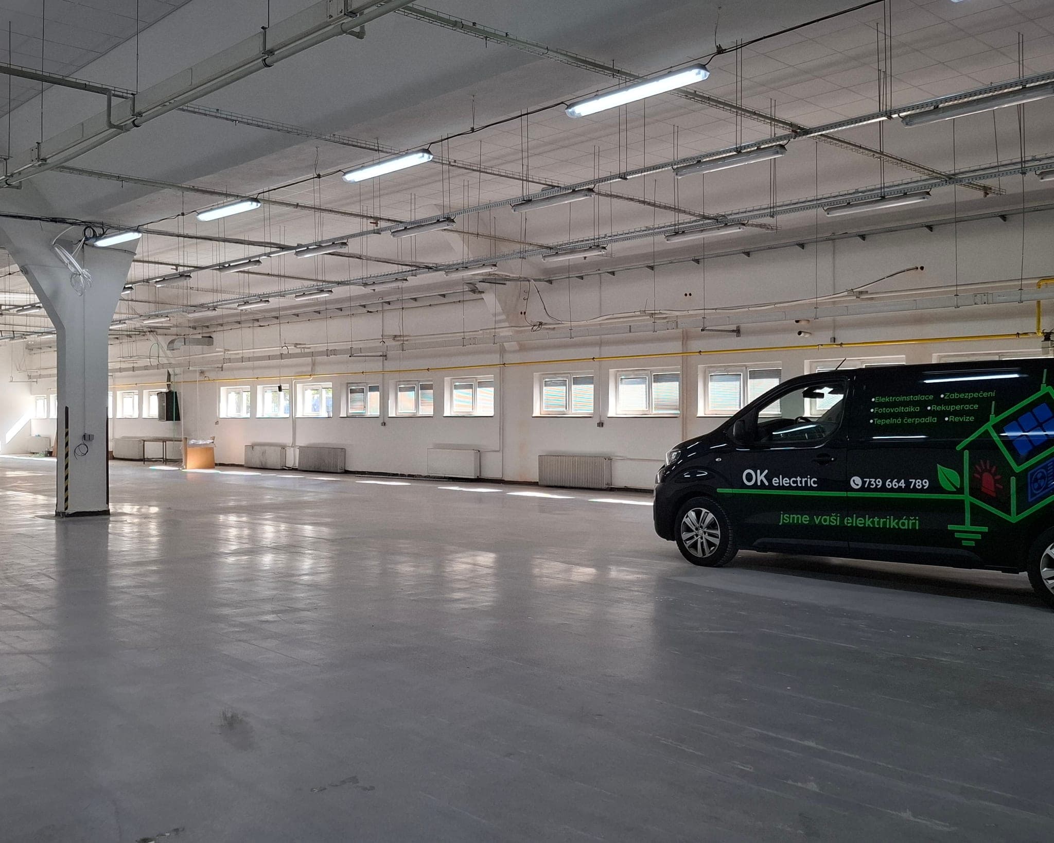 Vyklizená výrobní hala s novým řadovým osvětlením pod stropem a zaparkovanou dodávkou OK electric, České Budějovice